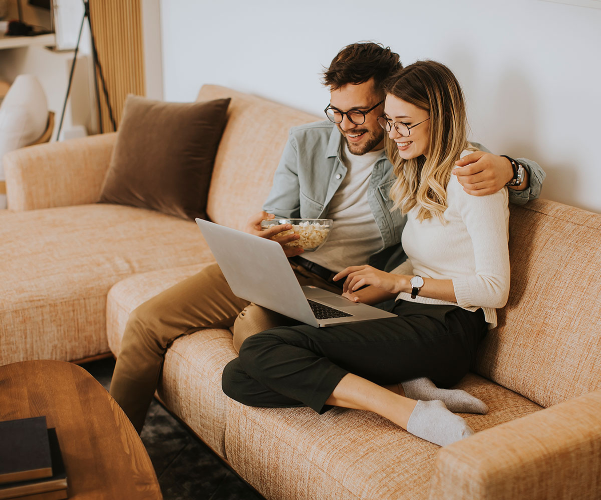 young-couple-using-laptop-together-while-sitting-o-PZG6JC2